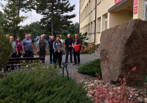 Uczestnicy rajdu stoją przed obeliskiem patrona szkoły