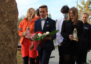 młodzież składa kwiaty pod tablicą pamiątkową