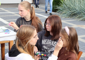 Wolontariuszki SK Caritas malują dziewczynkę