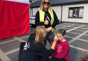 Wolontariuszki SK Caritas malują dziewczynkę