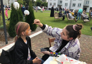 Wolontariuszka SK Caritas maluje dziewczynkę