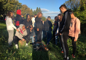 Uczestnicy wycieczki w Beskid Niski przy ognisku pieką kiełbaski