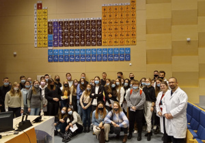 Technicy Analitycy wraz z prowadzącymi pokaz na tle układy okresowego pierwiastków chemicznych na auli Wydziału Chemii Uniwersytetu Jagiellońskiego.