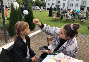Wolontariuszka SK Caritas maluje dziewczynkę