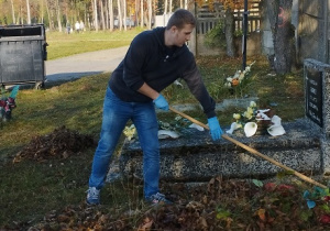 Jakub Antosik grabi liście na cmentarzu