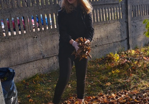 Julia Franoszczyk sprząta liście na cmentarzu