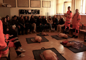 Uczniowie klasy przyrodniczej w mundurach ratowników medycznych przedstawiają profil klasy w sali 02 w budynku ZSP 8, zaproszeni goście siedzą i słuchają