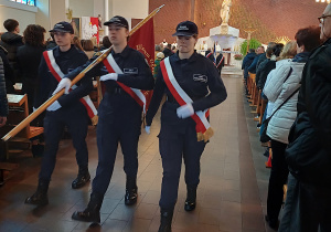 Uczniowie klasy policyjną maszerują ze sztandarem szkoły w kościele podczas uroczystych obchodów Święta Niepodległości