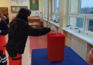 Uczennica klasy przyrodniczo- ratowniczej wrzuca kartę wyborczą do urny