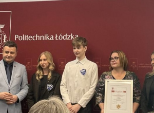 Uczniowie i pani dyrektor pozują do zdjęcia na ściance Politechniki Łódzkiej