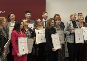 Dyrektorzy szkół pozują do zdjęcia na ściance Politechniki Łódzkiej